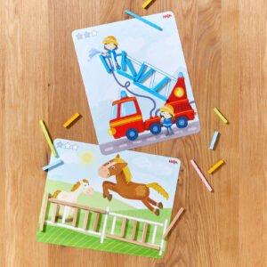 Two illustrated cards on a wooden surface, one with a fire truck scene and the other with jumping horses, surrounded by colorful rectangular sticks.