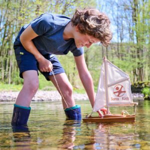 Child playing with a HABA Terra Kids DIY Catamaran in a natural setting